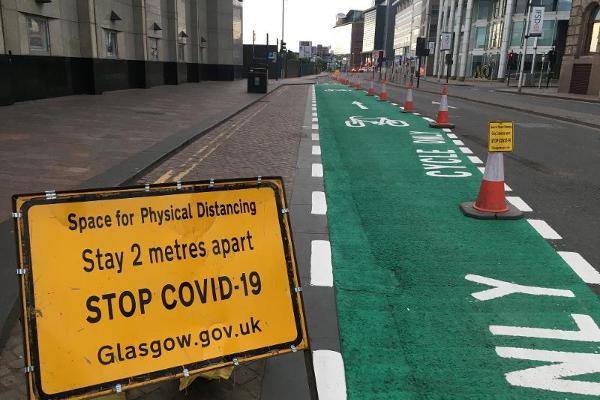 A road sign placed beside a cyclelane and widened pavement encourages physical distancing=