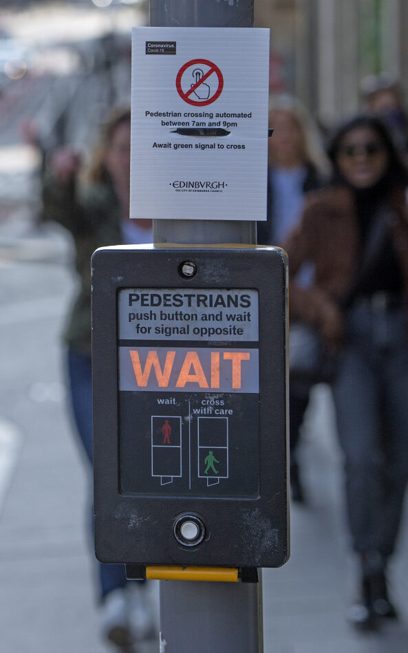 A sign above a pedestrian crossing control box advising that the crossing has been automated
