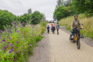 Individual cycling and group of friends walking along a new active travel path at Glasgow's Claypits