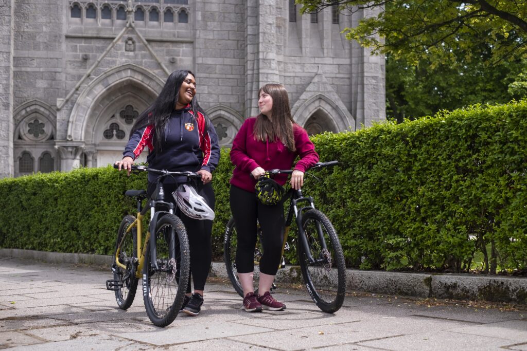 Two teenagers speaking next to their bicycles.