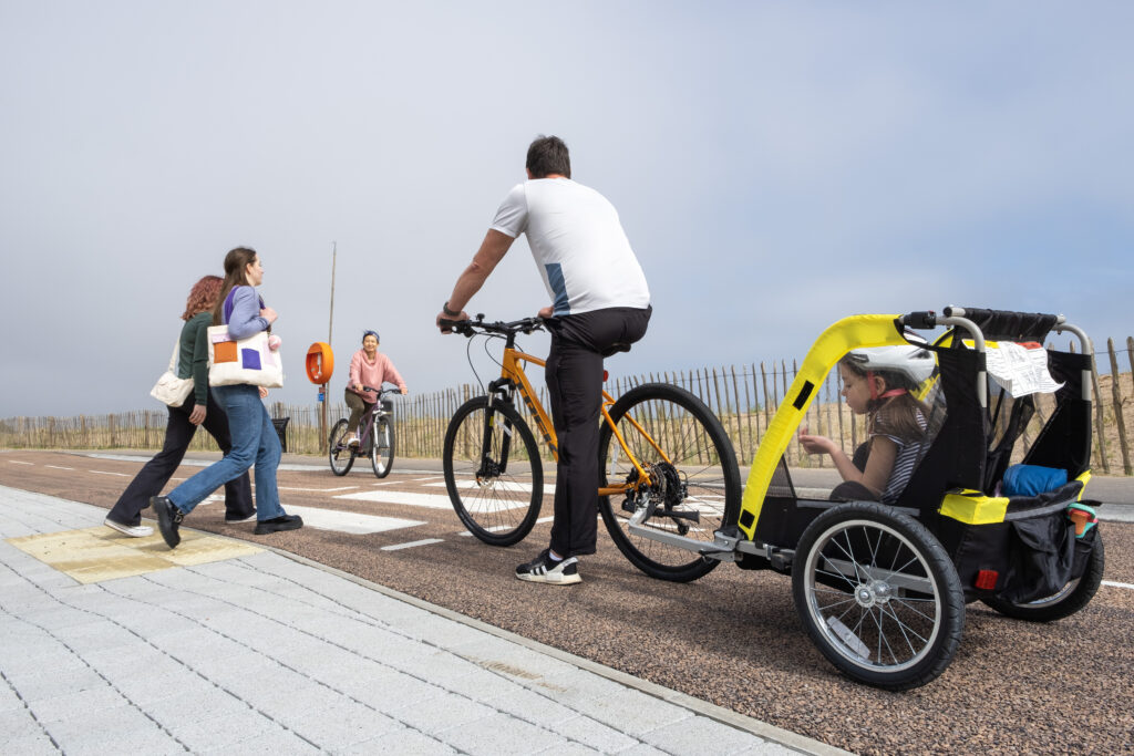 Pedestrians crossing a cycle path using zebra crossing

Cyclist paused at crossing in background

Cyclist with child in cycling trailer paused at crossing in foreground