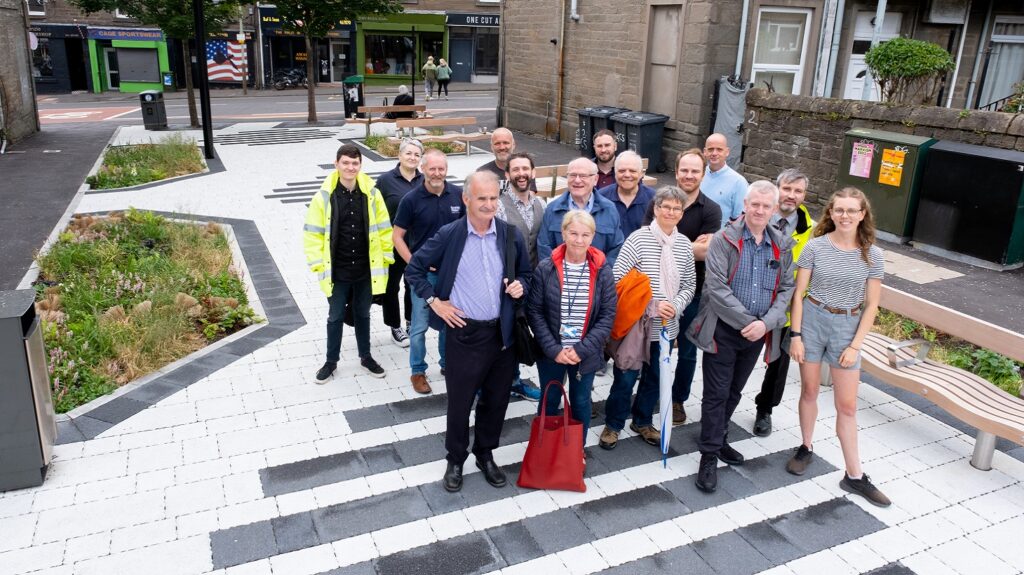 16 people involved in the project are shown standing on the large floor mural on Craigie Street.