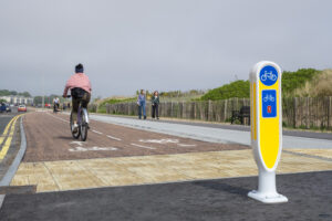 Woman cycling solo along segregated cycle lane by coast