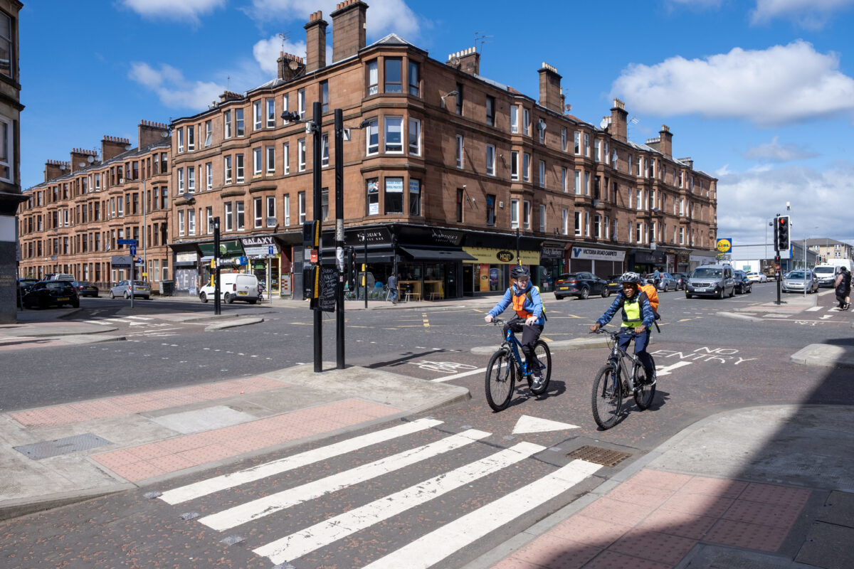 Two children cycling on a cycleway in Glasgow with businesses in the background