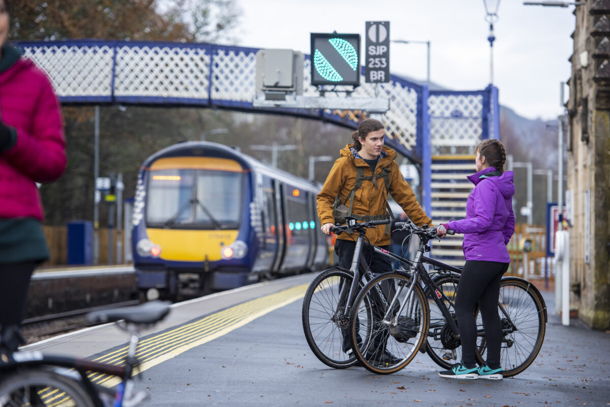Two cyclists on train platform in Pitlochry with train in background