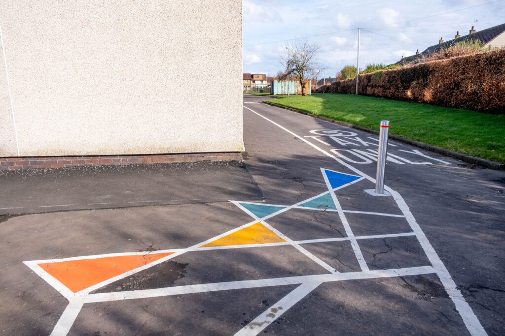 Part of the pedestrian walkway is shown. There is a colourful ground marking in the foreground.