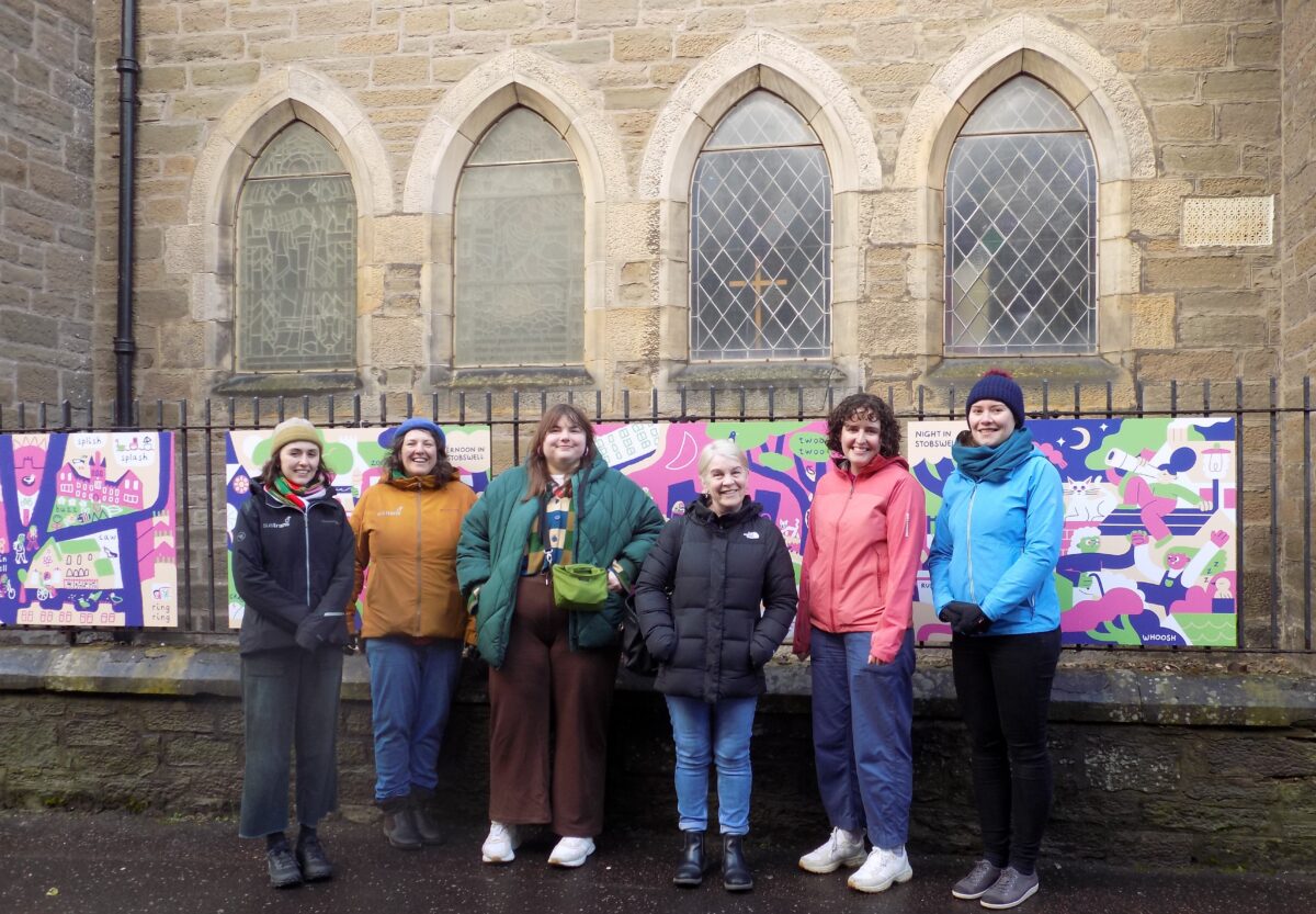 Six women standing in front of new artwork on railings