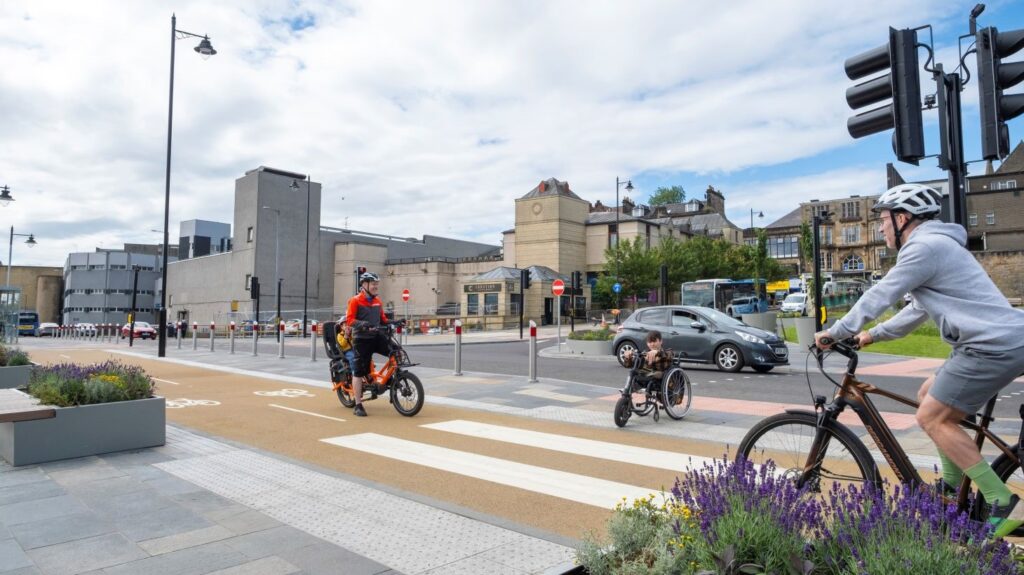 People wheeling and cycling on the forecourt at Stirling Train Station